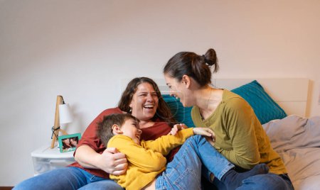 Familia de dos madres y su hijo jugando cosquillas en casa
