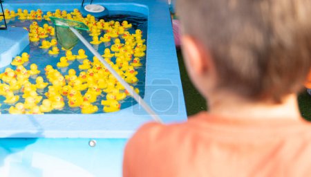 Boy playing a fairground game of catching rubber ducks