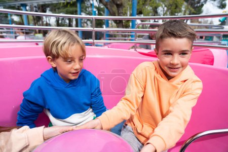 Two children at the amusement park. Friends having fun at the cup attraction