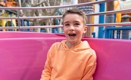 Garçon riant très heureux de l'attraction de la coupe dans un parc d'attractions
