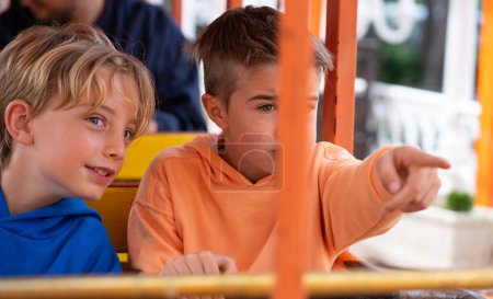 Dos niños montando el tren en un parque de atracciones