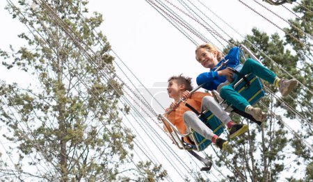 Niños montando una atracción voladora en un parque de atracciones