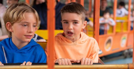 Deux enfants caucasiens en train dans un parc d'attractions