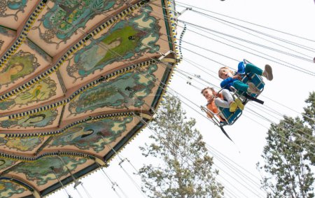 Dos niños montando una atracción voladora en un parque de atracciones con espacio para copias
