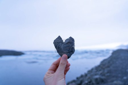 Herzförmiger Stein mit einer natürlichen Winterlandschaft dahinter. Liebe Island