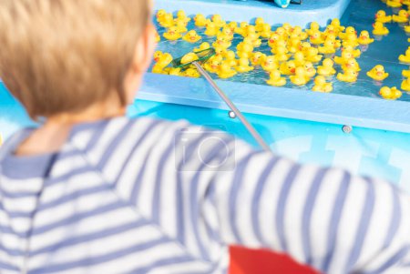 Boy fishing for rubber ducks with a net at a fair