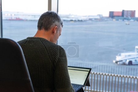 Man working with laptop waiting for a flight in an airport