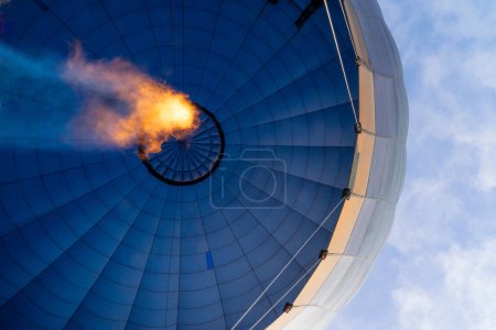 View from below of a hot air balloon heating the air with the flame seen from inside