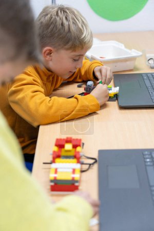 Téléchargez les photos : Les enfants apprennent à construire et programmer un robot dans une classe de robotique pour enfants - en image libre de droit