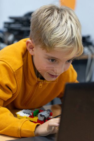 Garçon motivé utilisant un ordinateur dans une classe de robotique