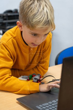 Enfant concentré dans un atelier de robotique regardant l'ordinateur