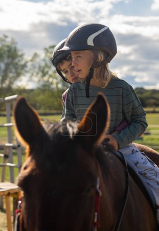 Two children riding horses together on a ranch