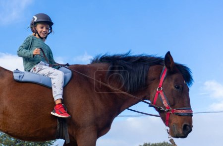 Child learning horseback riding on a farm