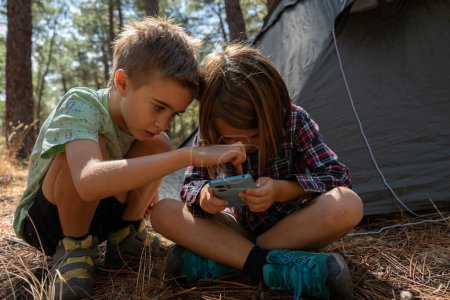 Kinder schauen gemeinsam im Wald auf Handys