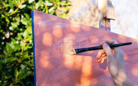 Brush painting on a canvas with coral, peach and pink and orange colors