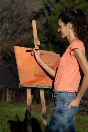 Frau malt ein abstraktes Gemälde mit Pfirsich und orangefarbener Acrylfarbe