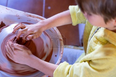 Boy learning to make pottery in a wheel class