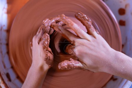 Child's hands molding a bowl on a potter's wheel