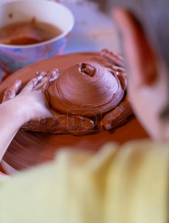 Boy shaping a piece of clay on a potter's wheel in a pottery workshop