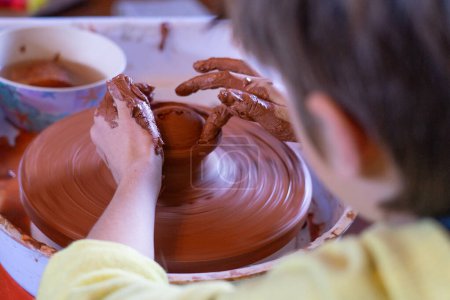 Boy making a clay figure on a potter's wheel