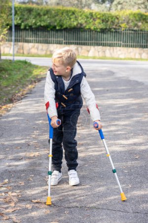 Boy walking with crutches down the street