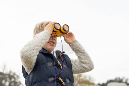 Niño mirando a través de binoculares en la naturaleza