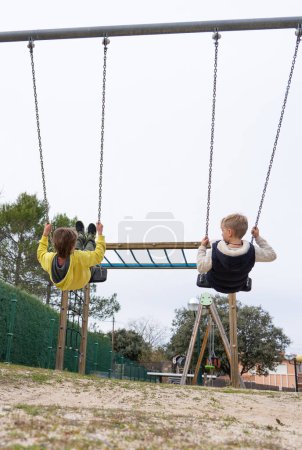 Two children swinging together on a swing