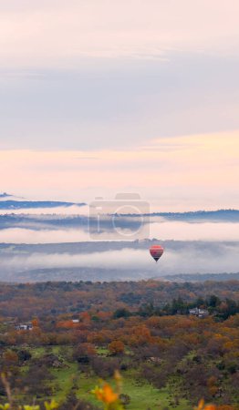 Heißluftballons fliegen im Morgengrauen über eine Landschaft mit Wolken