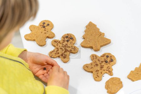 Child decorating homemade cookies with chocolate