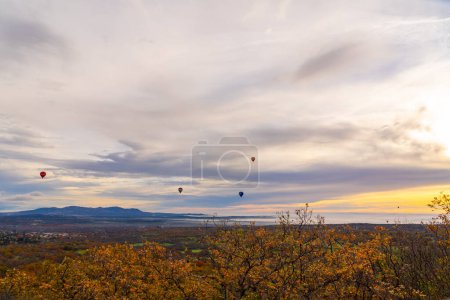 Hot air balloons flying over an autumn landscape