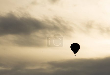Silhouette of a hot air balloon flying with a cloudy sky
