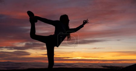 Silhouette einer Frau beim Yoga bei Sonnenaufgang