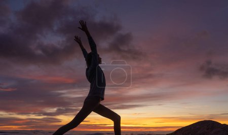 Silhouette de femme faisant une pose de yoga au coucher du soleil