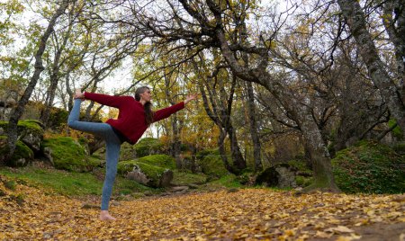 Frau posiert im Herbst bei Yoga im Wald mit Kopierraum