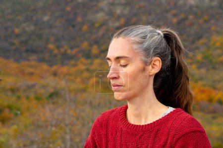 Frau mittleren Alters meditiert in der Natur