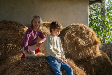 Zwei Kinder sitzen auf einem Bauernhof im Heu