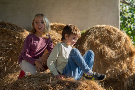 Two children on the hay of a farm playing