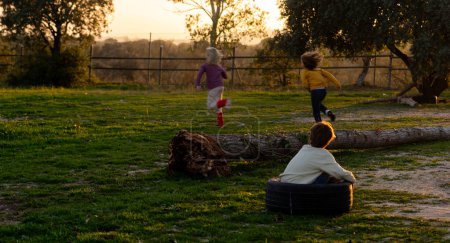 Drei Kinder spielen bei Sonnenuntergang auf dem Feld