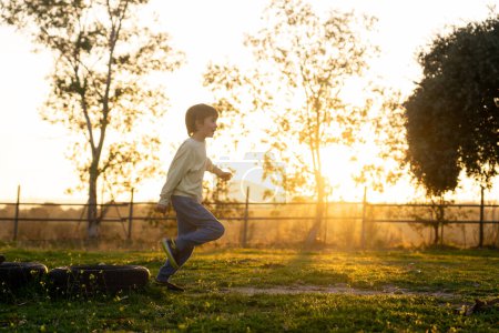Junge läuft bei Sonnenuntergang auf Feld