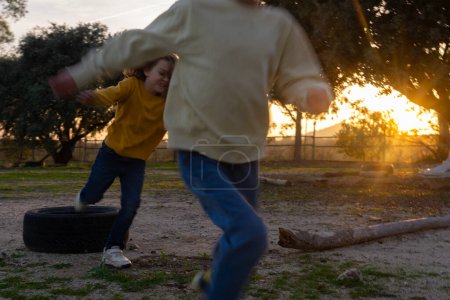 Children running through the field at sunset