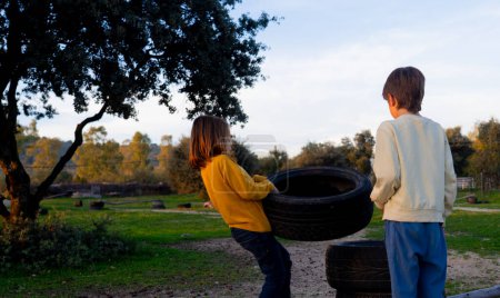 Two children playing with tire wheels