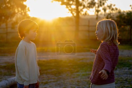 Two children playing in nature at sunset