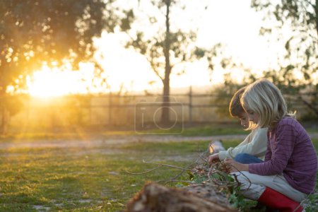 Kinder spielen bei Sonnenuntergang in der Natur mit einem Baumstamm