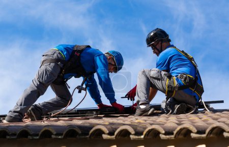 Téléchargez les photos : Travailleurs sur un toit installant des panneaux solaires - en image libre de droit