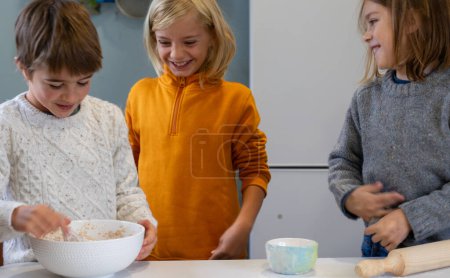 Tres niños felices cocinando juntos en casa
