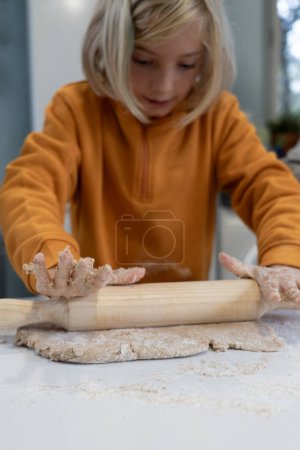 8 year old boy kneading dough to make pizza at home