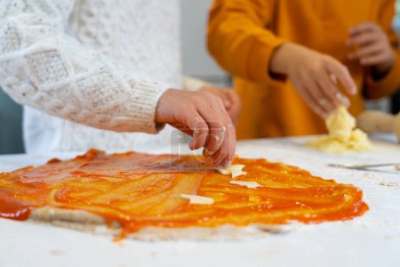 Téléchargez les photos : Two children making a pizza together at home - en image libre de droit
