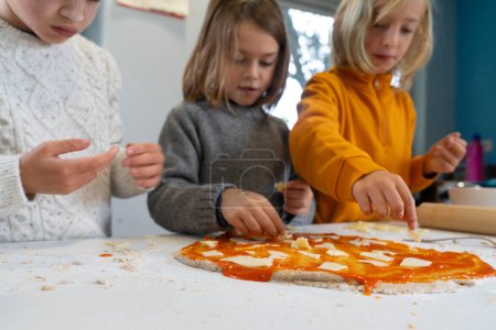 Children cooking pizza in a home kitchen