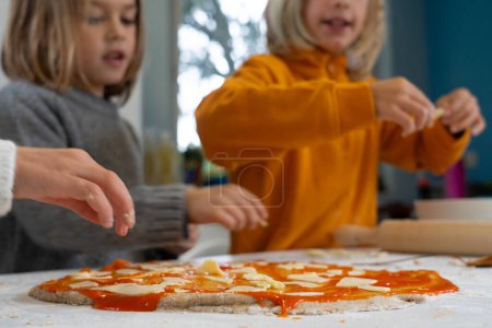 Children cooking a homemade pizza together at home