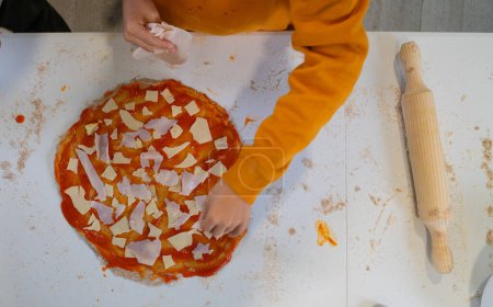 Boy making a homemade pizza seen from above